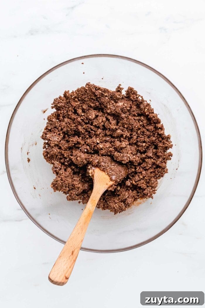 Creamy No-Bake Vegan Peanut Butter Pie 3 A crumbly chocolate mixture in a bowl with a wooden spoon.