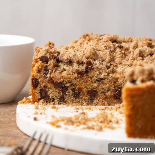 A sliced chocolate chip coffee cake sitting on a white serving dish.