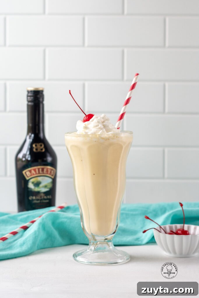 Homemade Milkshake Recipes for Every Craving 6 a milkshake in a footed glass with a red and white straw in it, next to a bottle of baileys Irish creme.