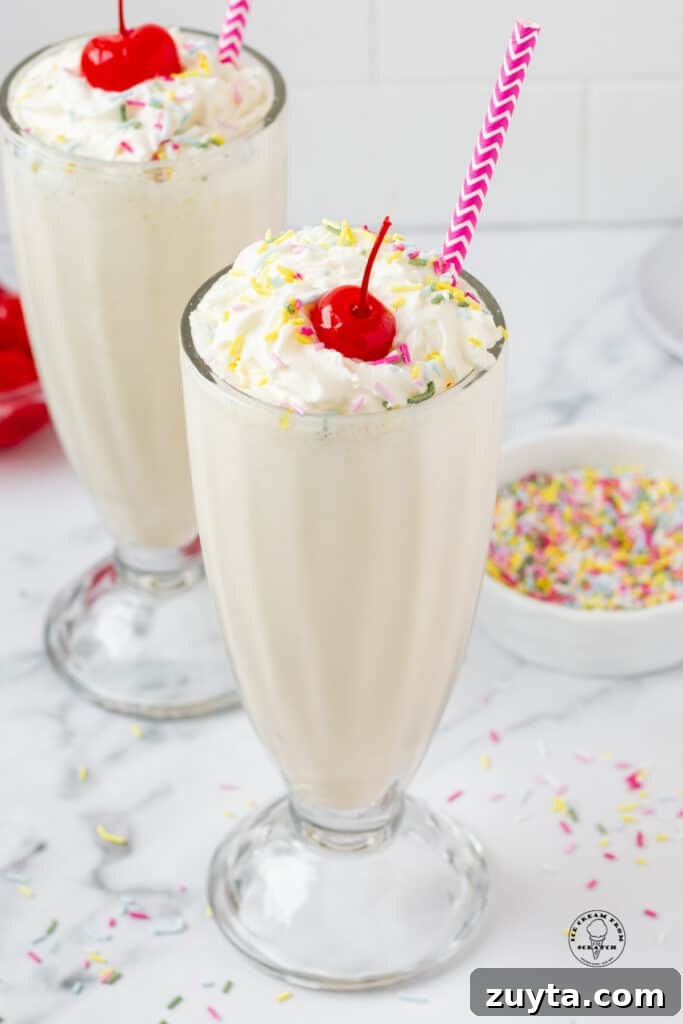 Homemade Milkshake Recipes for Every Craving 8 two vanilla milkshakes with purple straws, topped with whipped cream, sprinkles, and cherries