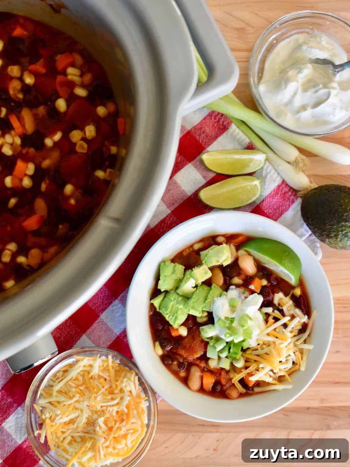 Slow Cooker Three-Bean Vegetarian Chili Recipe 2 Three bean vegetarian chili in the slow cooker with sour cream, cheese, green onions, and avocado.