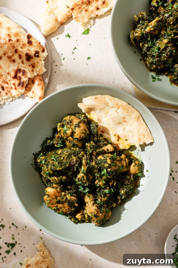 Creamy Chicken Saag with Spinach 8 A blue bowl with Palak Chicken and naan ready to be eaten.