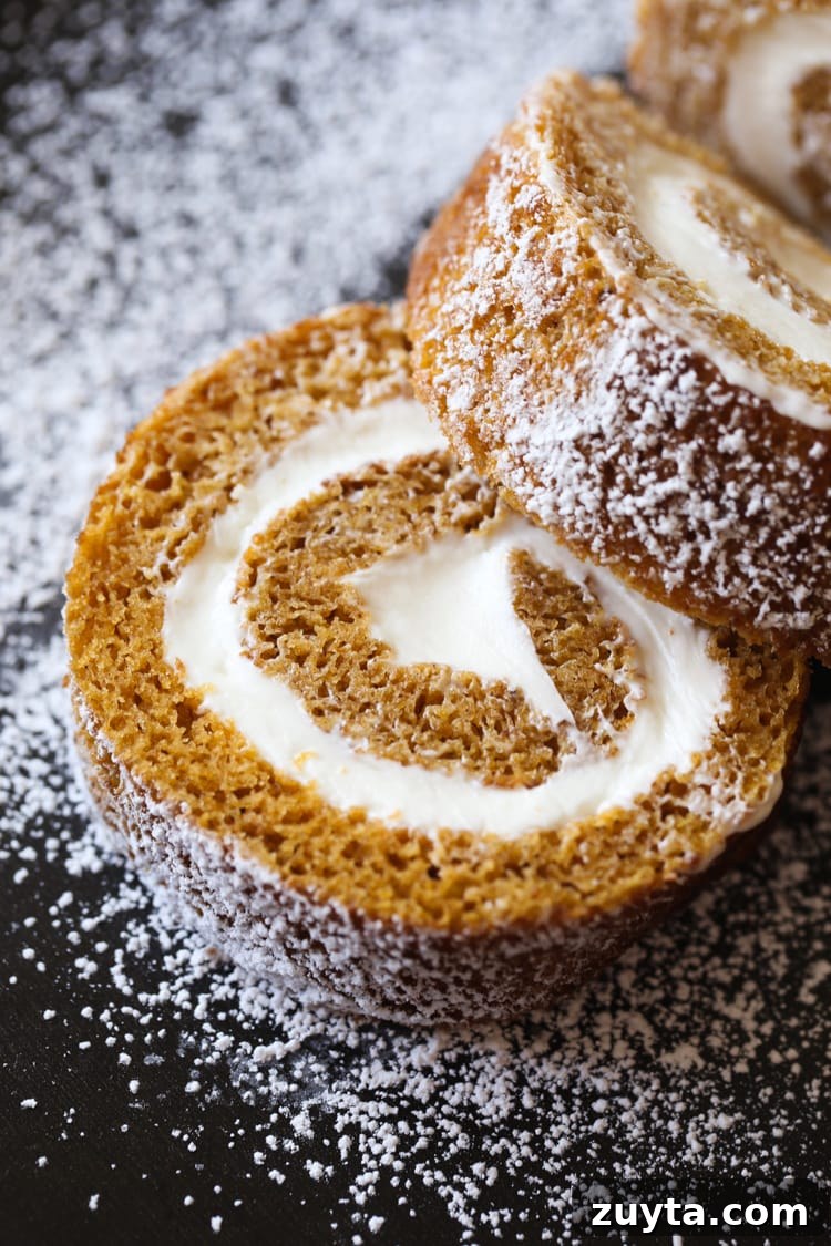 Close up of slices of a pumpkin roll dusted with powdered sugar.