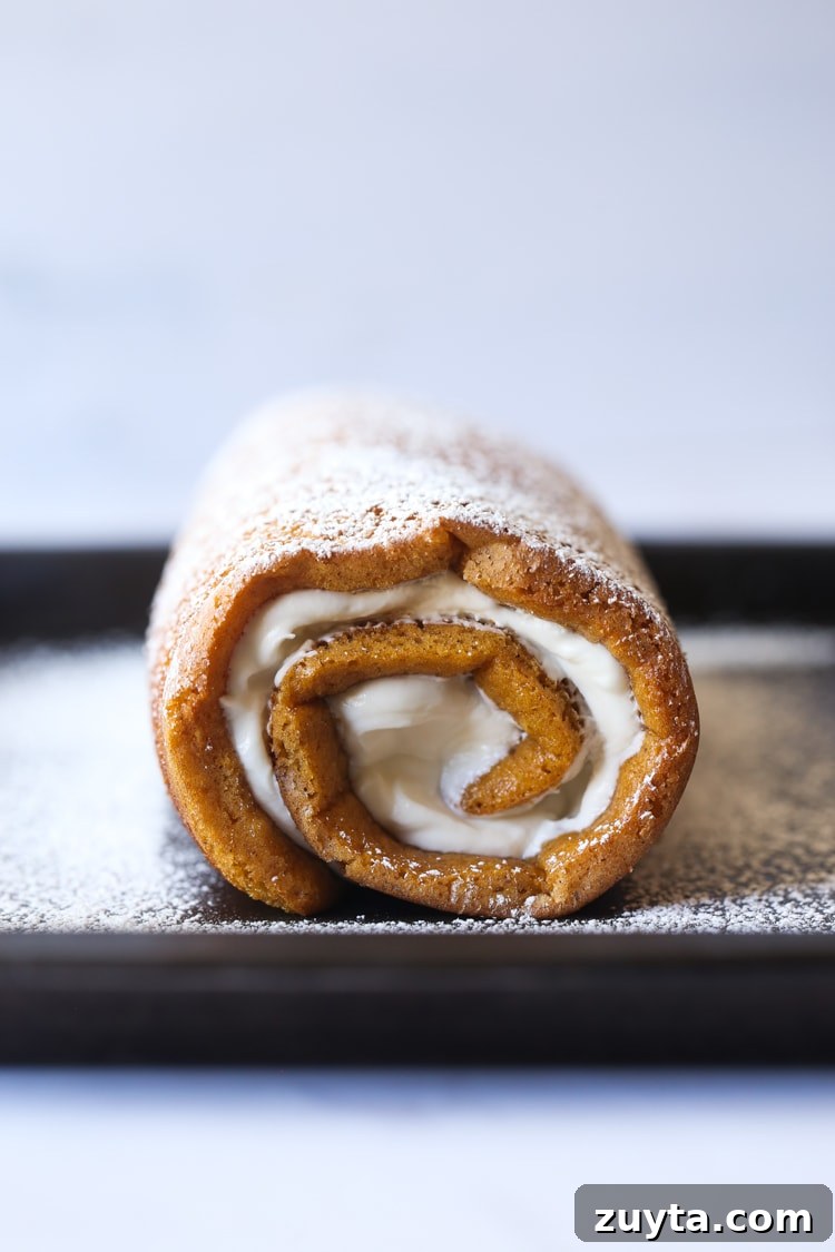Rolled up pumpkin roll with powdered sugar.