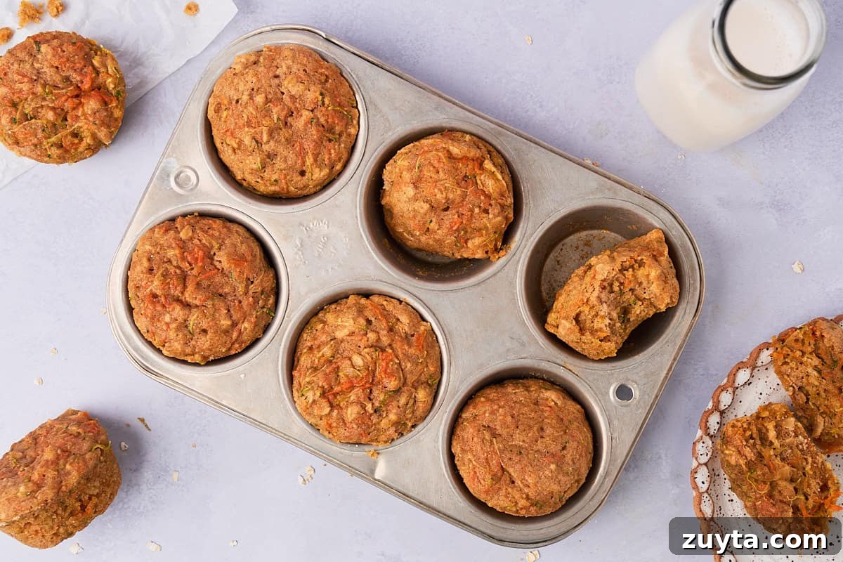 One-Bowl Zucchini Carrot Muffins Recipe 7 baked muffins in a muffin tin broken in half so you can see the insides
