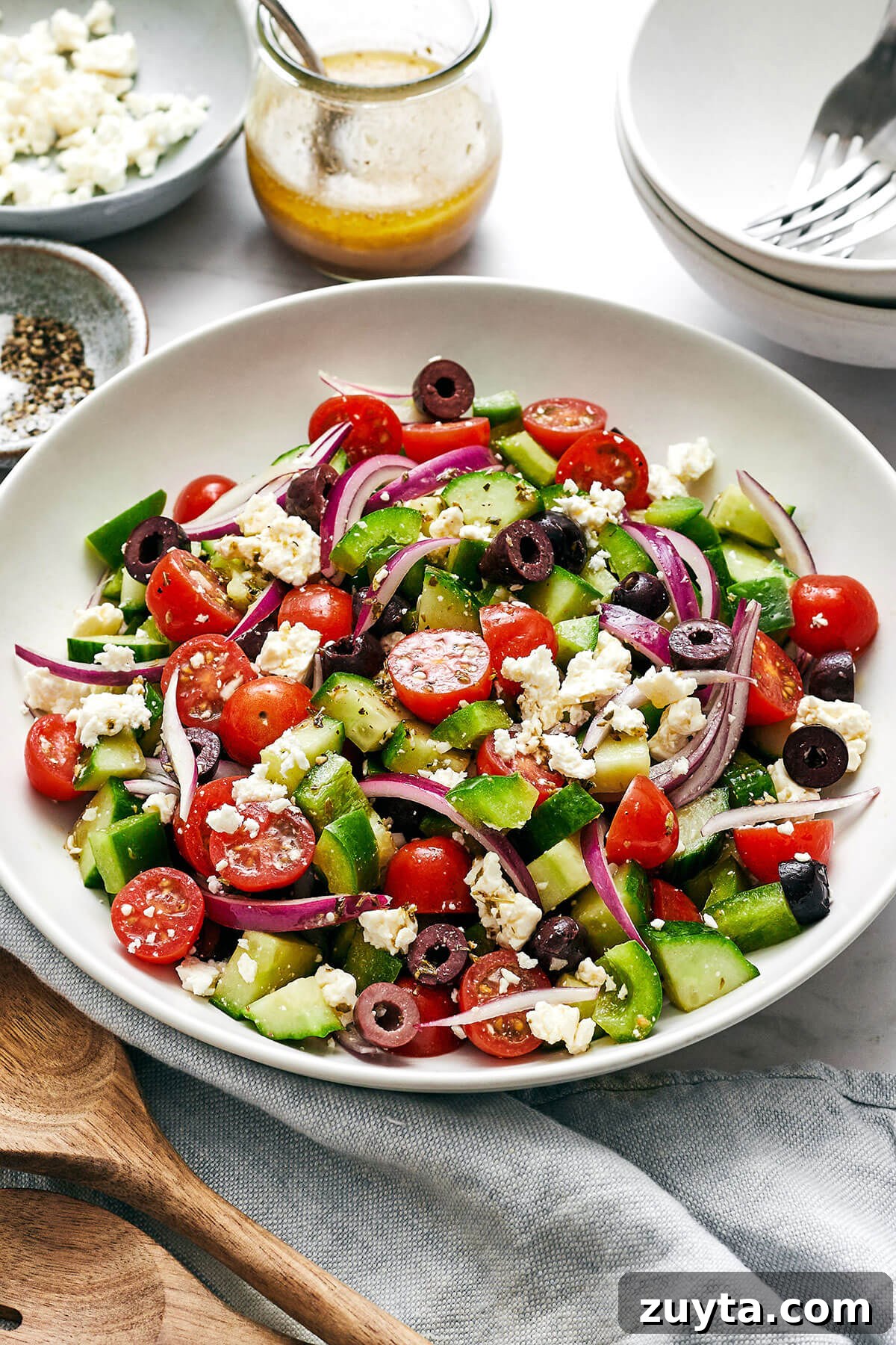 Over 60 Mediterranean Diet Recipes for Every Meal 12 Greek salad in a white bowl next to dressing.