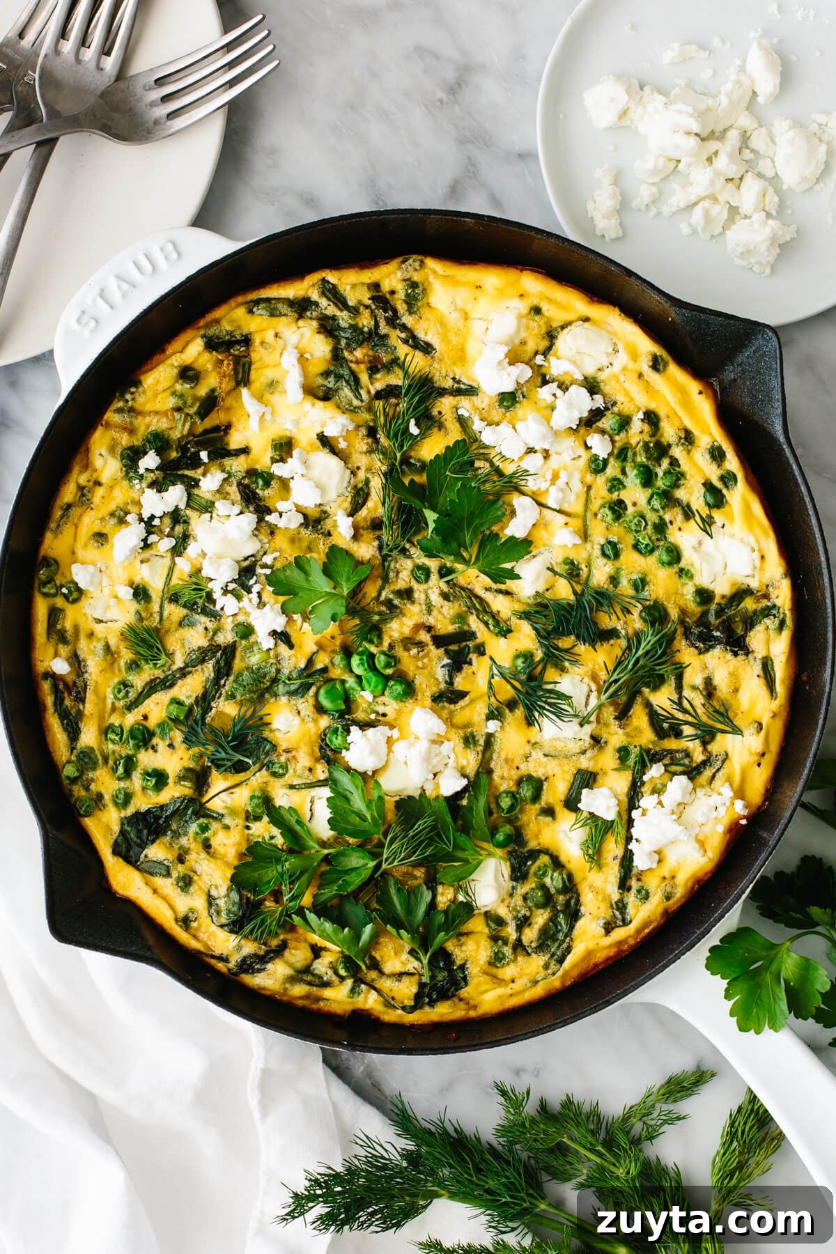 Over 60 Mediterranean Diet Recipes for Every Meal 19 Spring vegetable frittata in a skillet on a table.