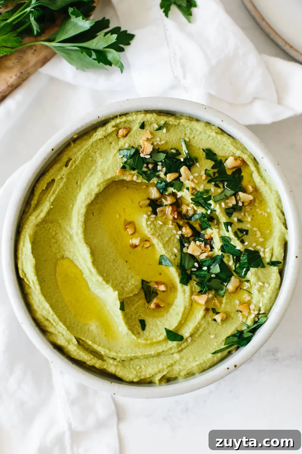 Over 60 Mediterranean Diet Recipes for Every Meal 28 Green hummus in a bowl with herbs and toppings.