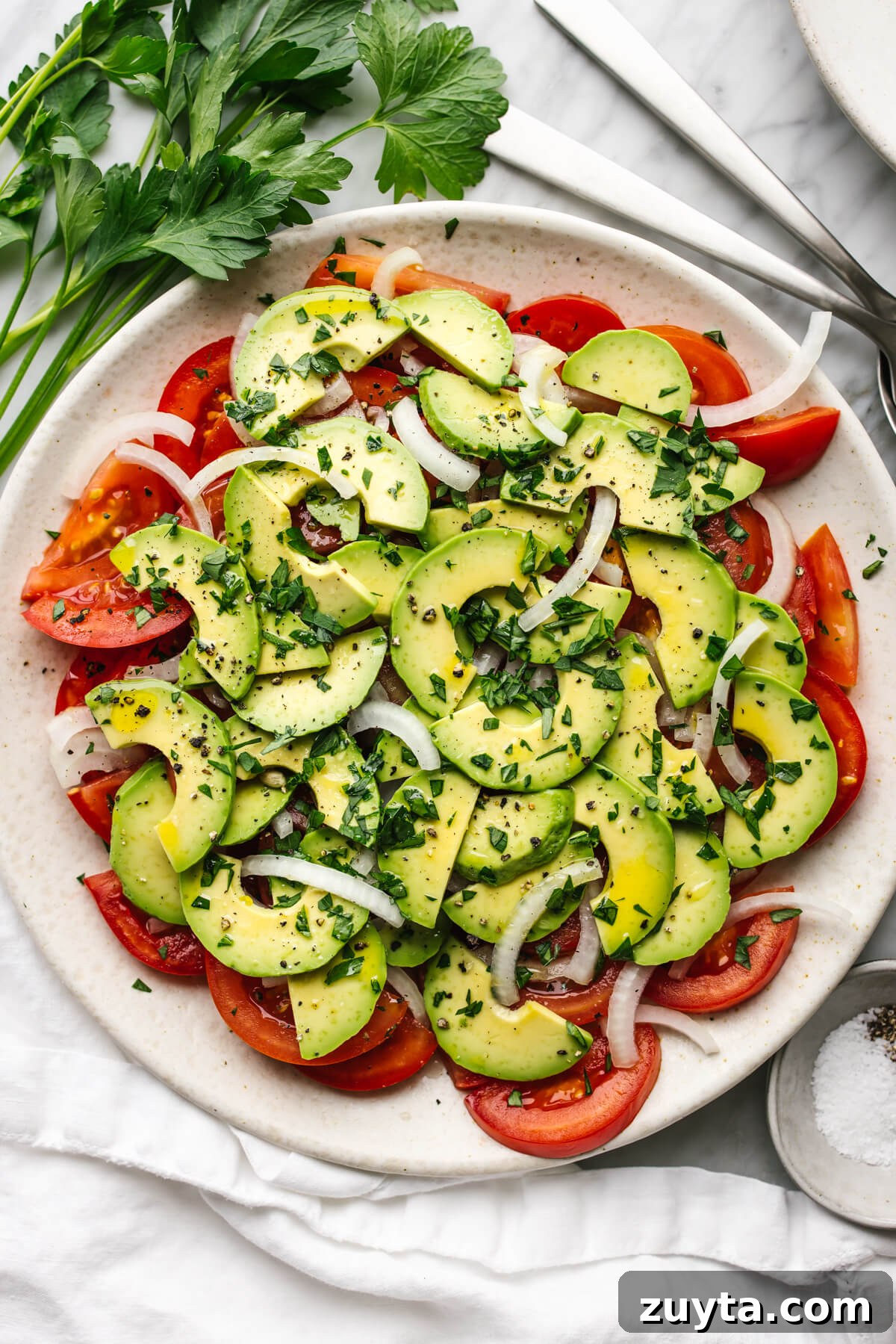 Over 60 Mediterranean Diet Recipes for Every Meal 42 Tomato, onion, avocado salad on a plate next to parsley.