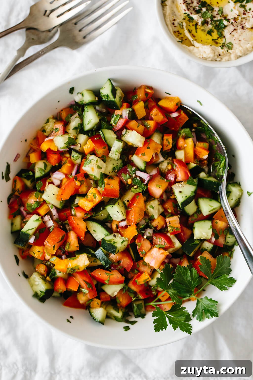 Over 60 Mediterranean Diet Recipes for Every Meal 43 Israeli salad made from tomatoes, cucumber, bell pepper, red onion and herbs in a white bowl.