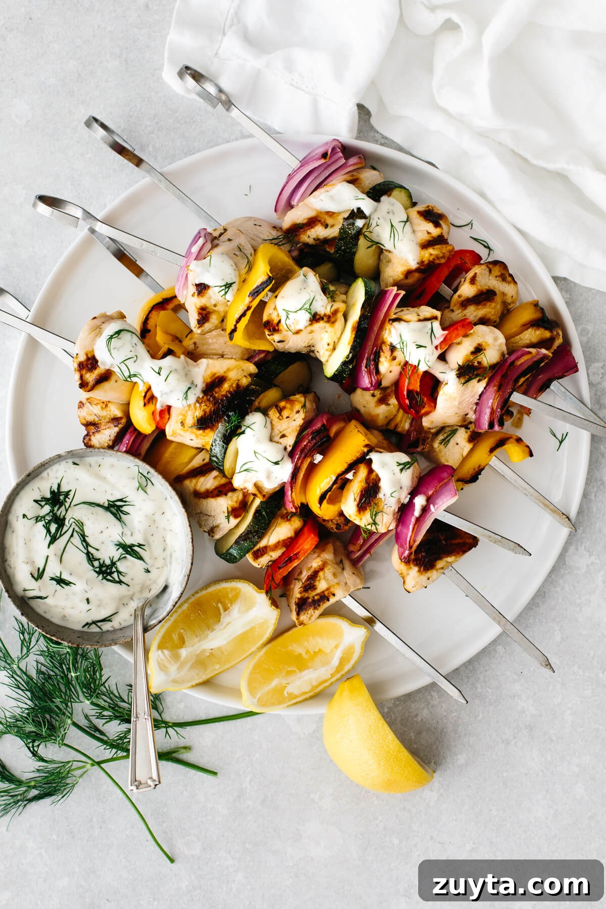 Over 60 Mediterranean Diet Recipes for Every Meal 74 Greek chicken kabobs on a white plate with tzatziki sauce.
