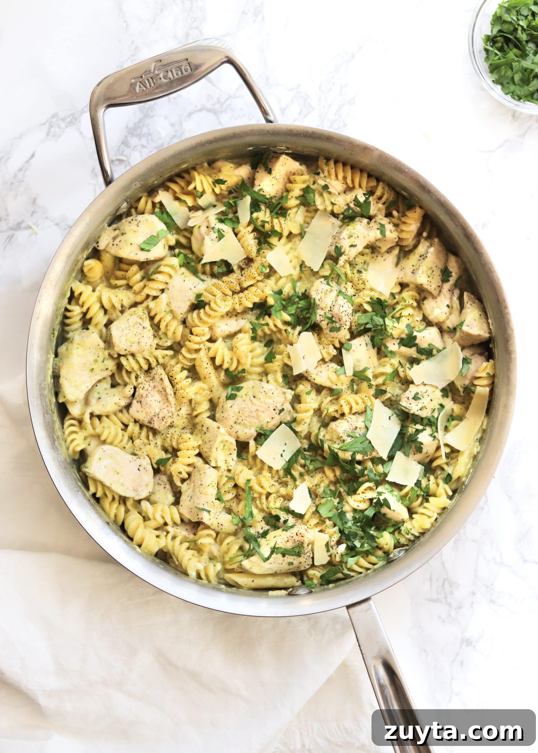 One-Pot Creamy Pesto Chicken Pasta Recipe 5 Finished pesto chicken pasta with a sprinkle of parsley and extra cheese in sauté pan