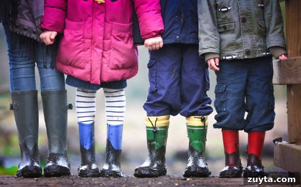 A group of kids posing for the camera wearing rain boots.