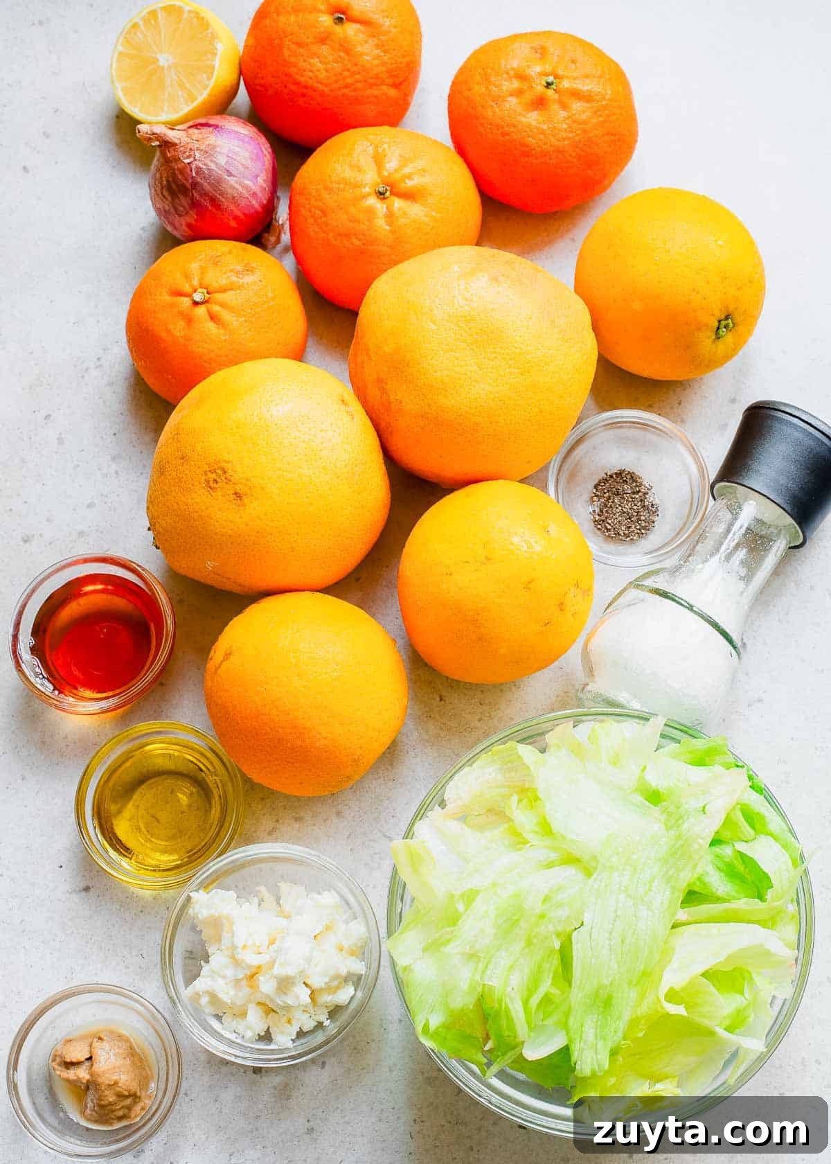 Zesty Citrus Salad with Orange, Grapefruit and Mint 2 Citrus laying on a counter top and a bowl of lettuce with other ingredients for a salad dressing.
