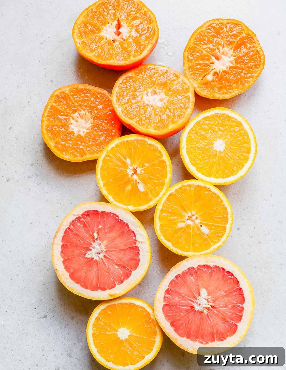 Zesty Citrus Salad with Orange, Grapefruit and Mint 3 Sliced oranges and grapefruits on a white surface.