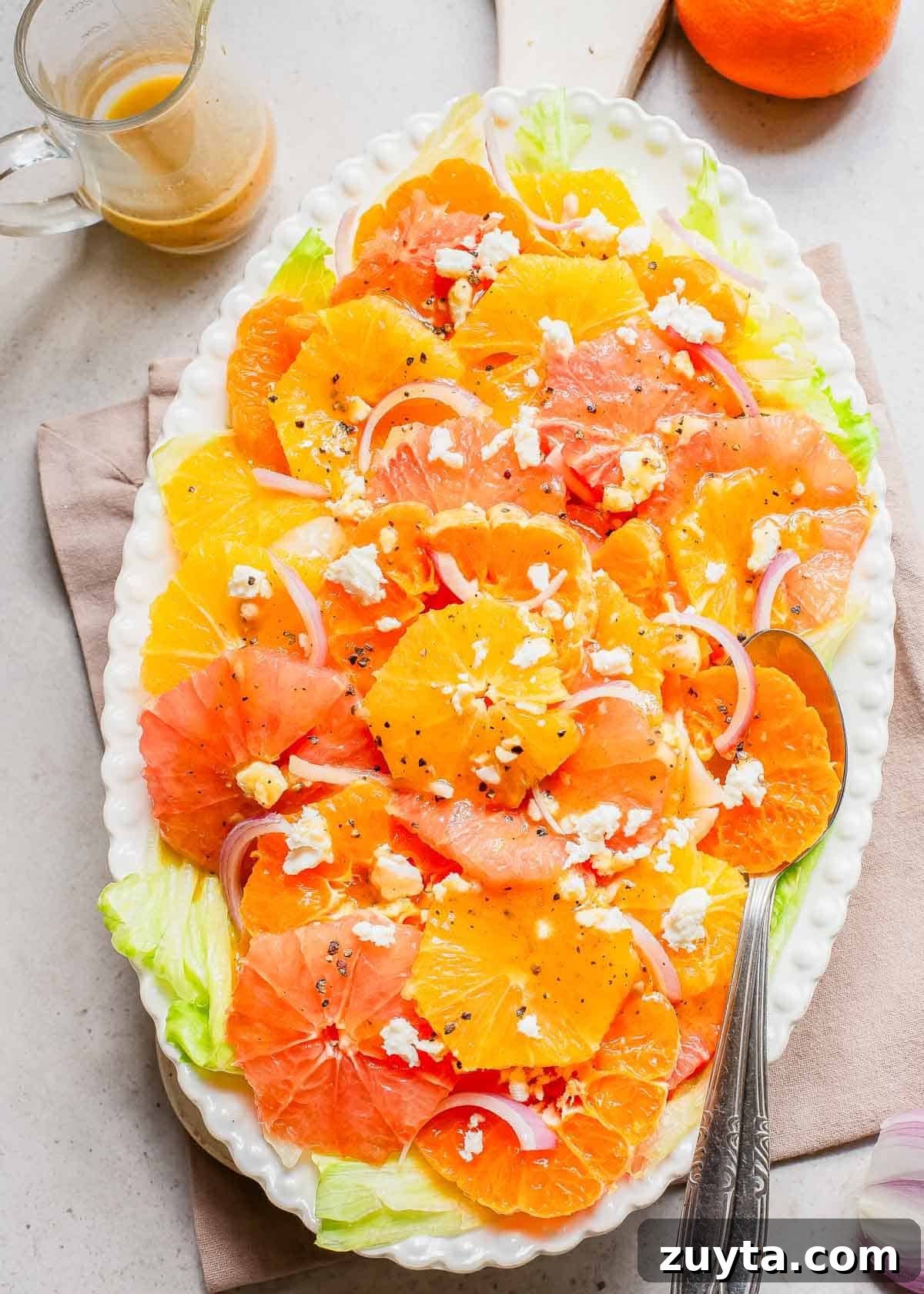 Zesty Citrus Salad with Orange, Grapefruit and Mint 5 Orange, grapefruit and mandarin salad on a white plate with a spoon.