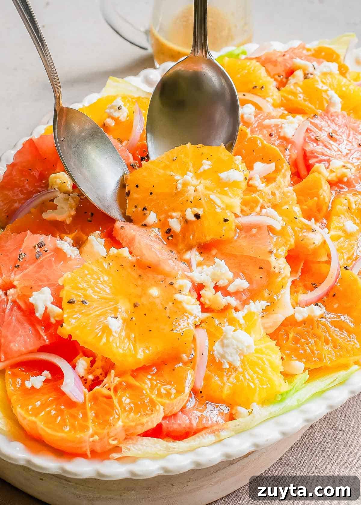 Zesty Citrus Salad with Orange, Grapefruit and Mint 6 A serving plate with citrus salad and two serving spoons.