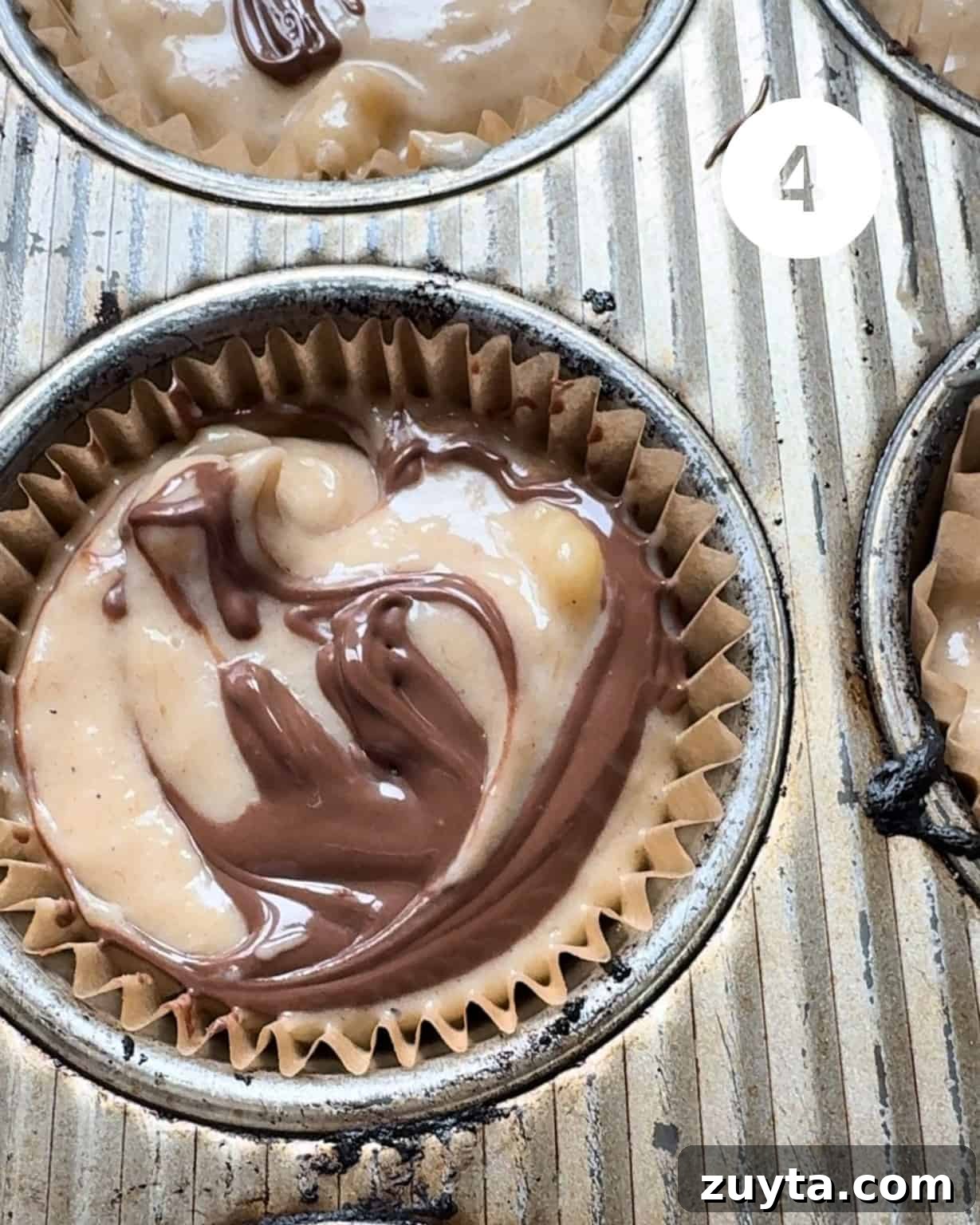 muffin batter in a muffin cup with nutella swirled on top