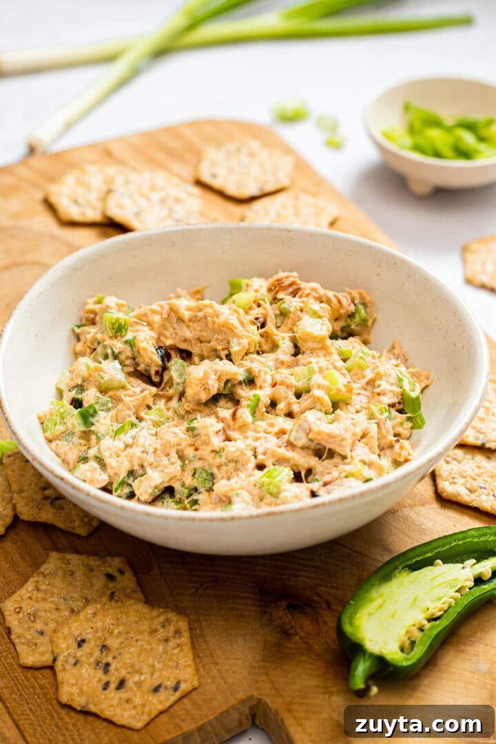 Spicy tuna salad in a white bowl on a wood serving board