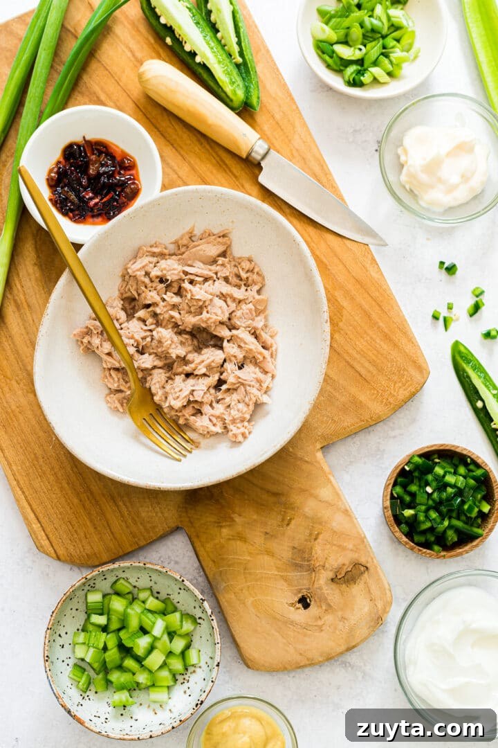 Ingredients for spicy tuna salad displayed in serving bowls on a wooden board