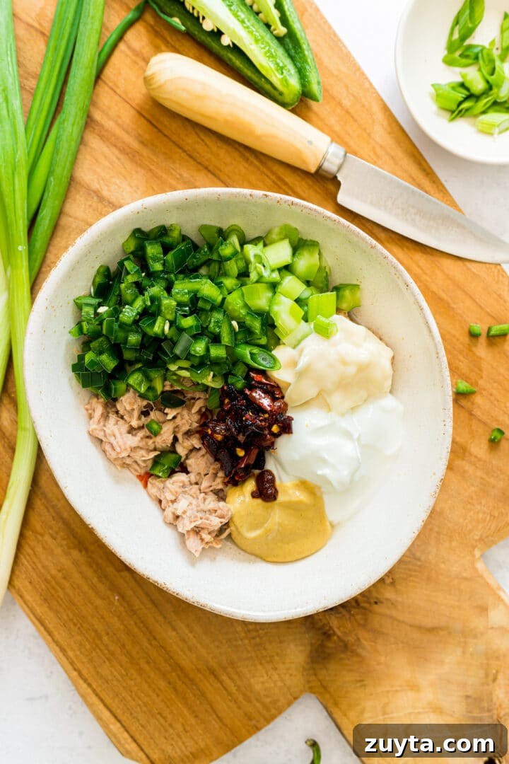 Ingredients for spicy tuna salad in a white bowl, unmixed