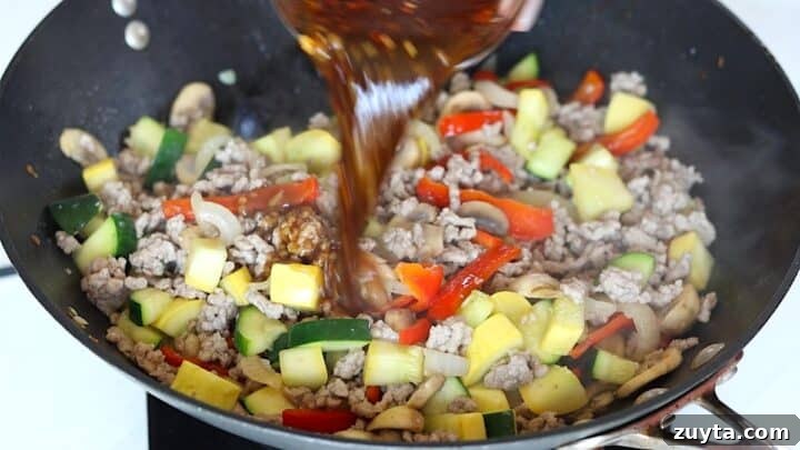 15-Minute Ground Pork Stir-Fry Recipe 6 Pouring the stir fry sauce over the ground pork stir-stir fry in a wok.
