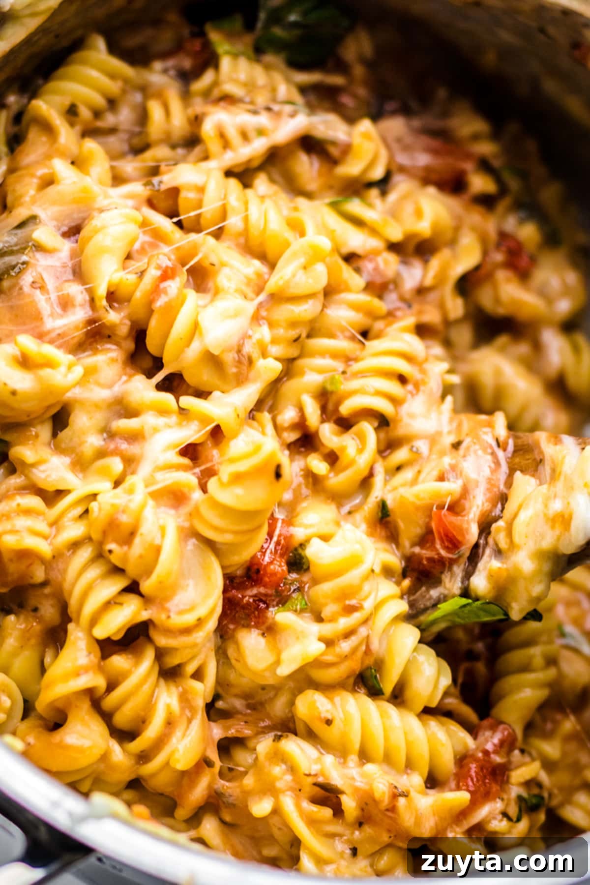 cheesy rotini pasta noodles being mixed together in pot.