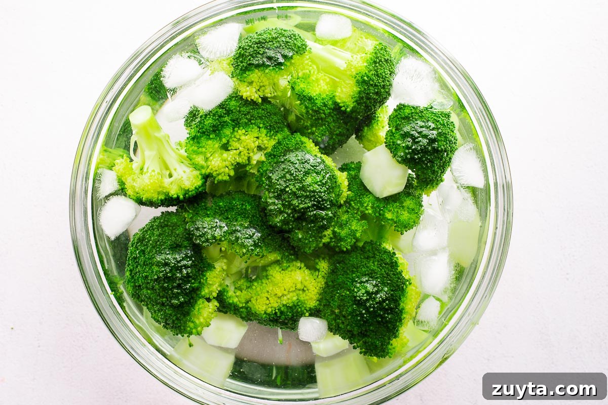 Broccoli florets chilling in an ice bath, viewed from above.