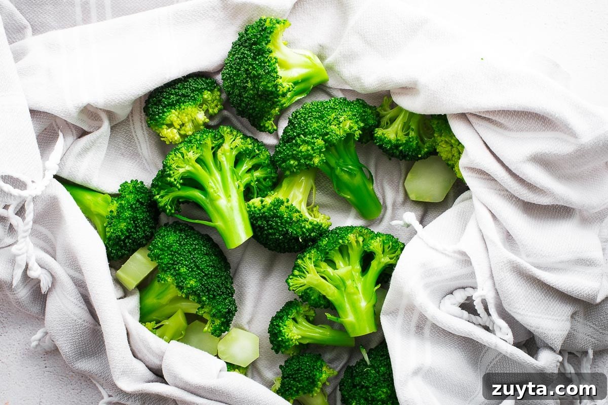 Drying cold, blanched broccoli florets with a kitchen towel.