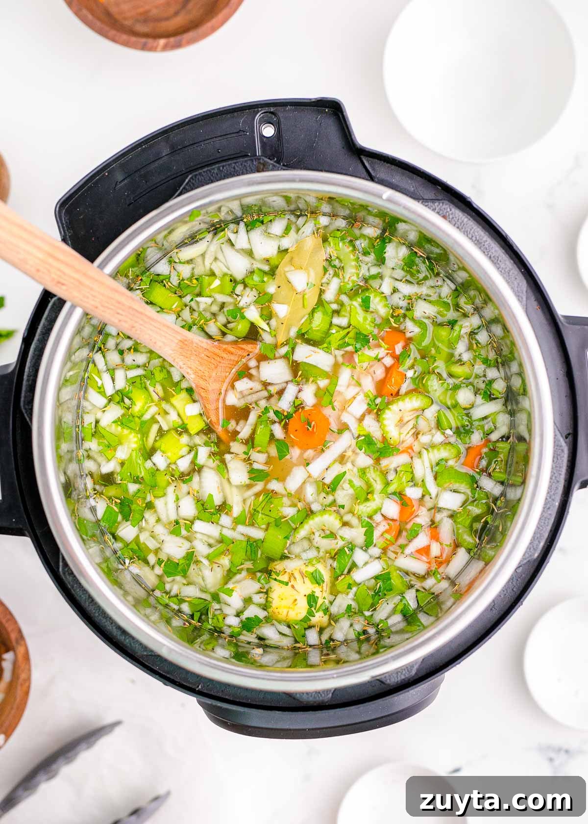 Ingredients added to an instant pot to make chicken noodle soup.