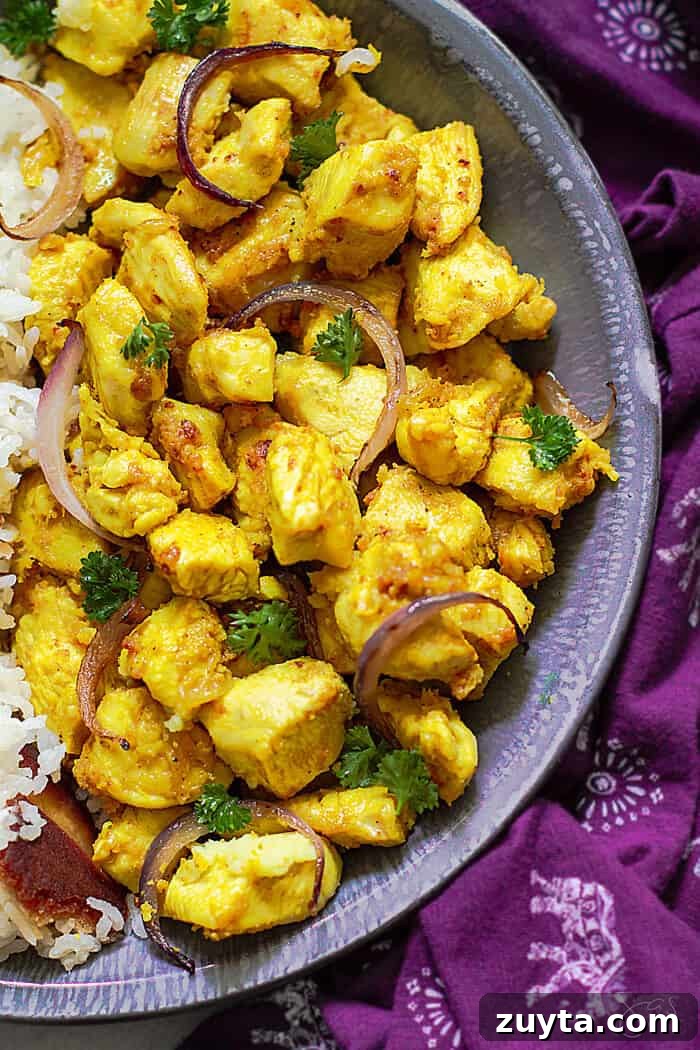 Ginger Garlic Indian Chicken Recipe 2 An overhead close up shot of half the dish with bright yellow Indian chicken with purple towel as a background