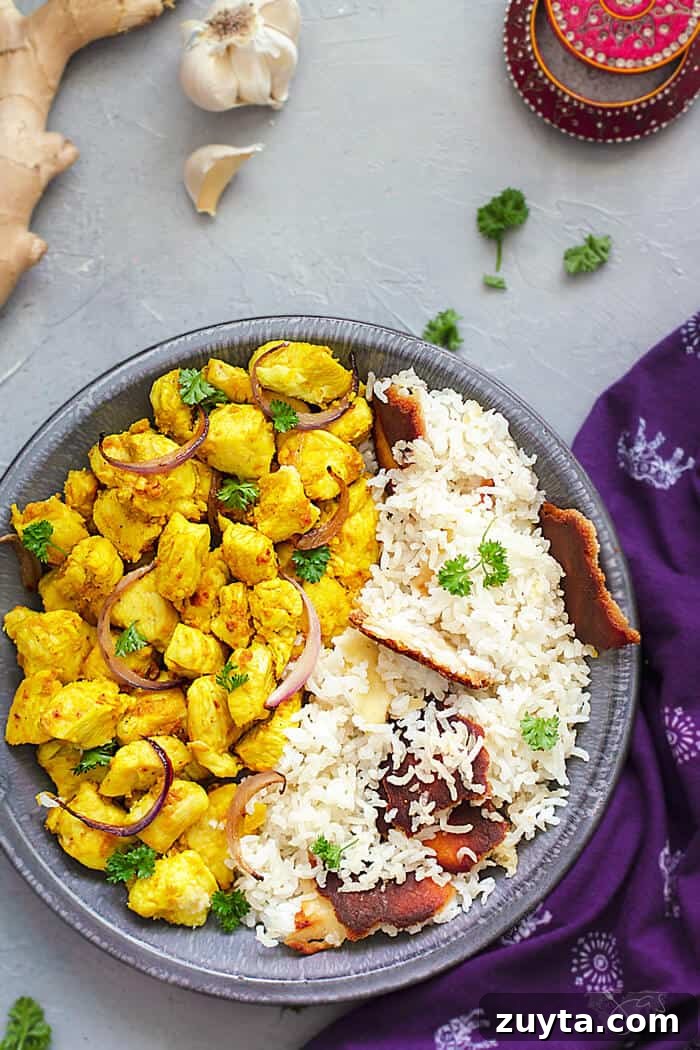 Ginger Garlic Indian Chicken Recipe 4 A flat lay of the chicken dish and rice in a shallow bowl with ginger and garlic around it.