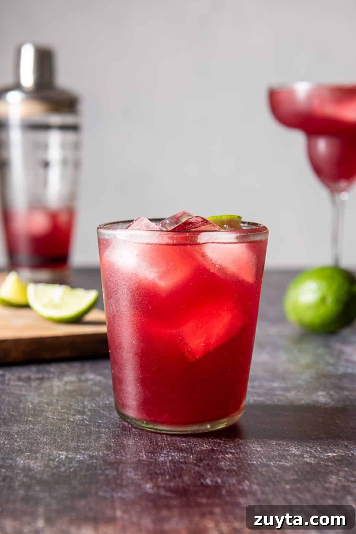 Pomegranate Margarita Cocktail Recipe 6 Double old fashioned glass filled with the red margarita with another glass in the back as well as limes and the shaker
