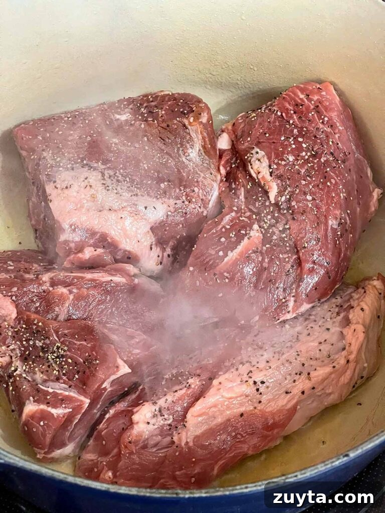 Slow-Braised Apple Cider Pork Shoulder 4 Pork shoulder browning in a dutch oven.