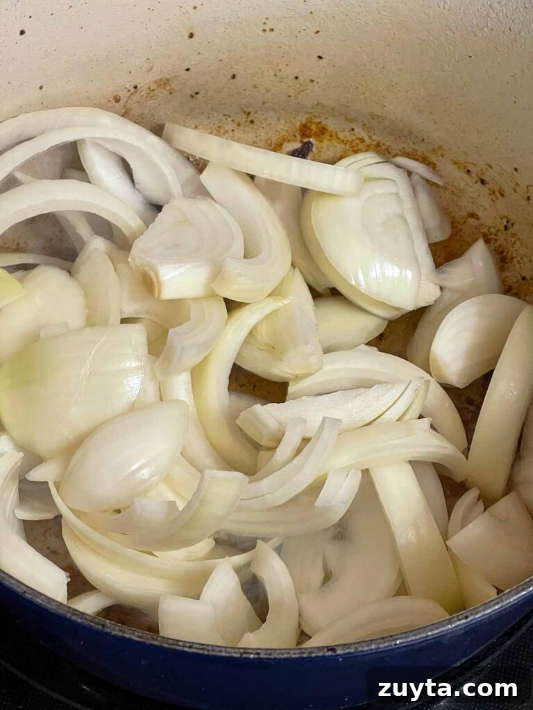 Slow-Braised Apple Cider Pork Shoulder 6 Onions just put into a dutch oven with fond on the bottom.