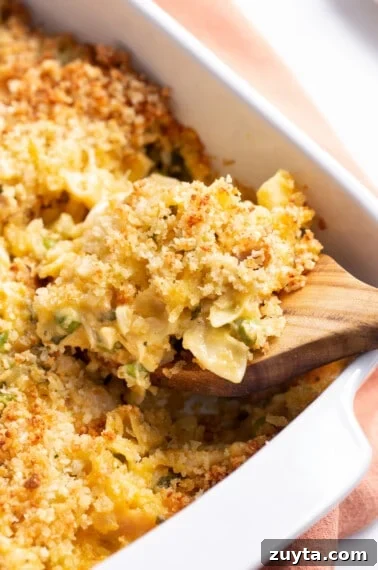 Leftover turkey casserole in a baking dish being scooped with a wooden spoon.