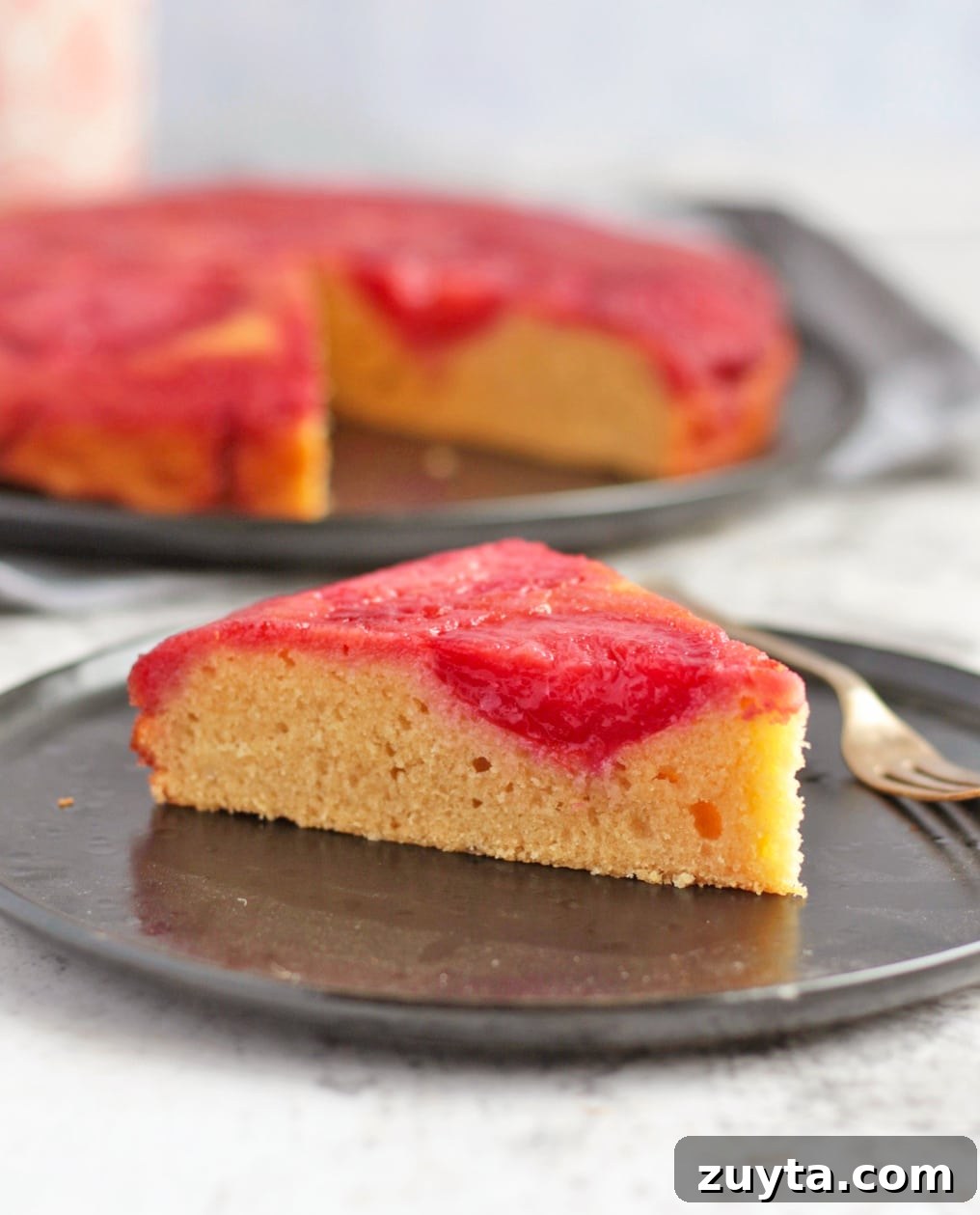 Caramelized Plum Upside-Down Cake Recipe 5 A slice of plum cake on a black plate.