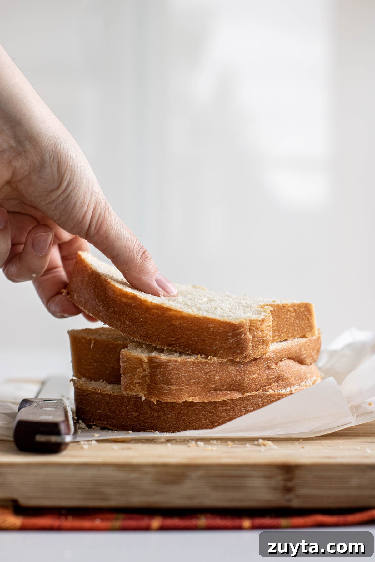 Make Sourdough Sandwich Bread in One Day 16 Hand grabbing a slice of sandwich bread.
