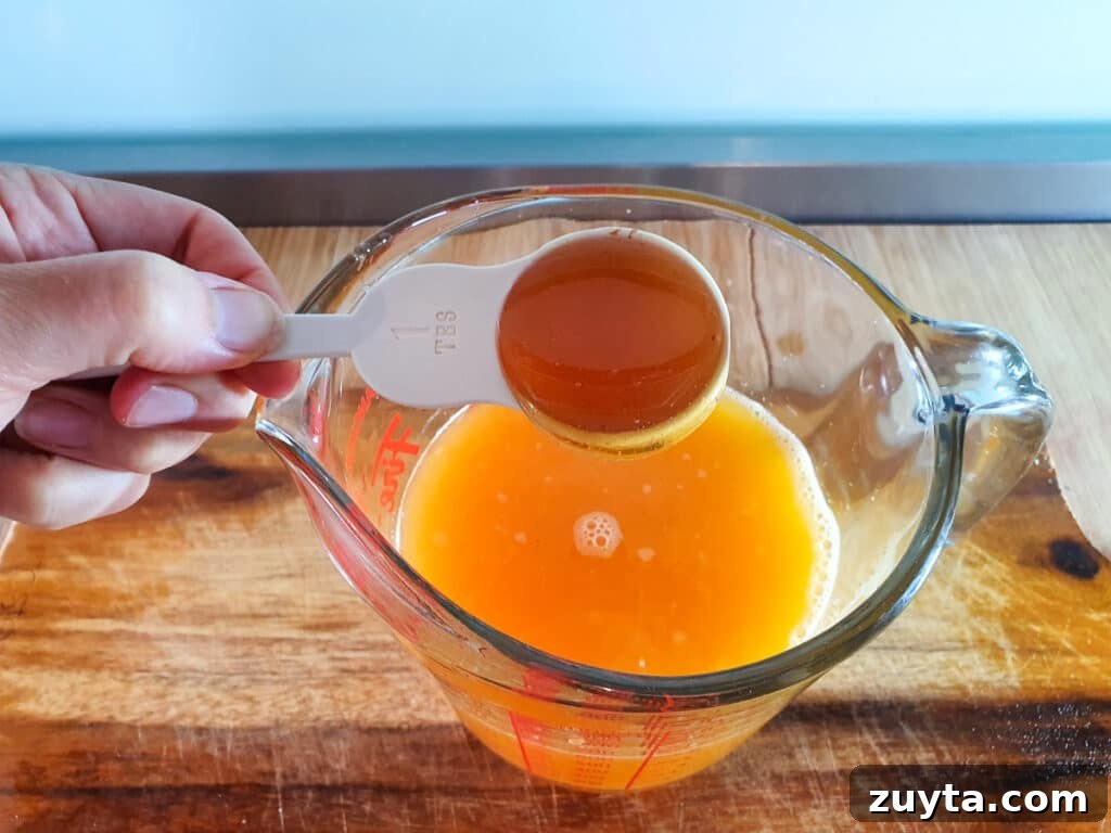 Homemade Orange Popsicles Recipe 6 Adding honey to orange juice.