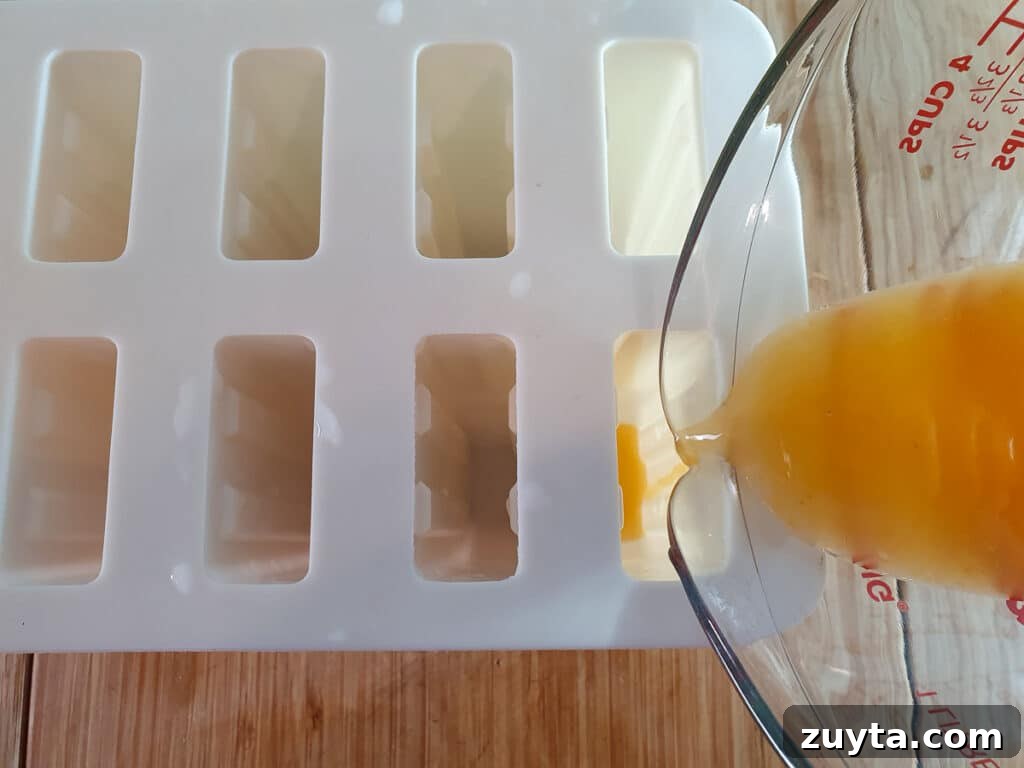Homemade Orange Popsicles Recipe 7 Pouring popsicle mix into molds.
