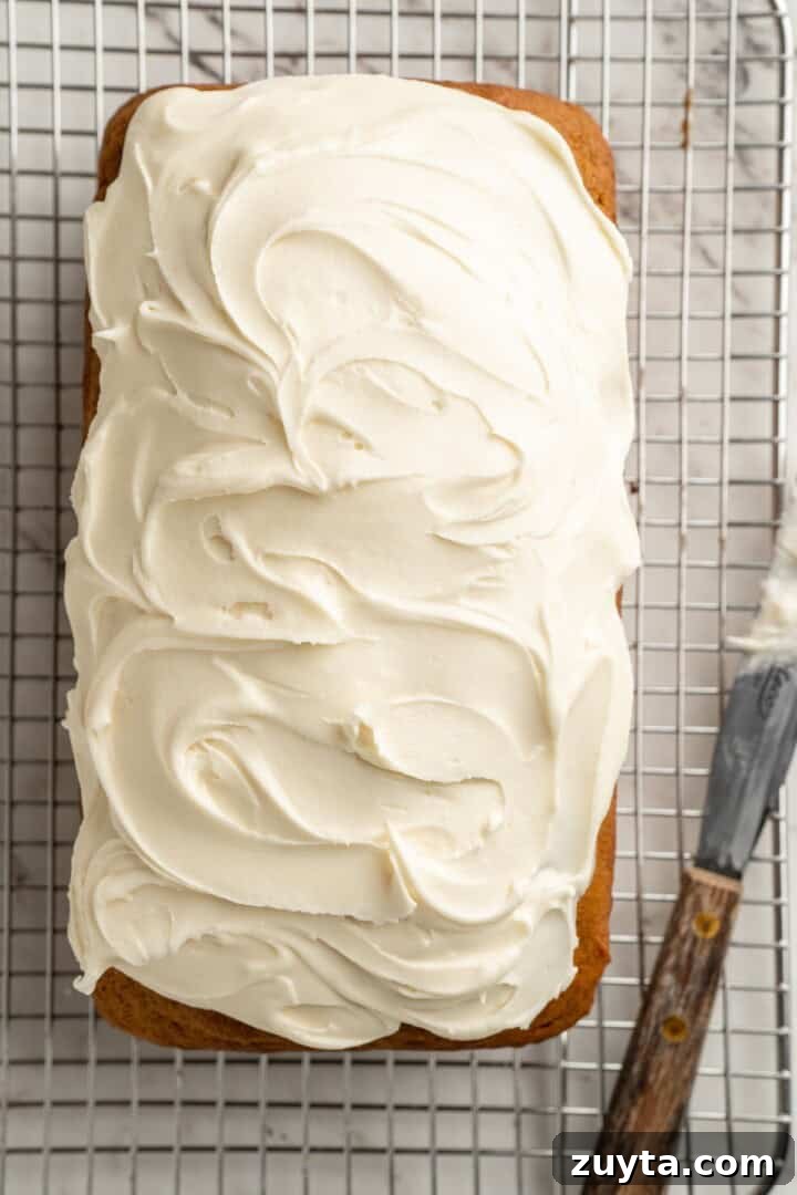 Frost cool bread. Overhead view of pumpkin bread with cream cheese frosting on wire rack