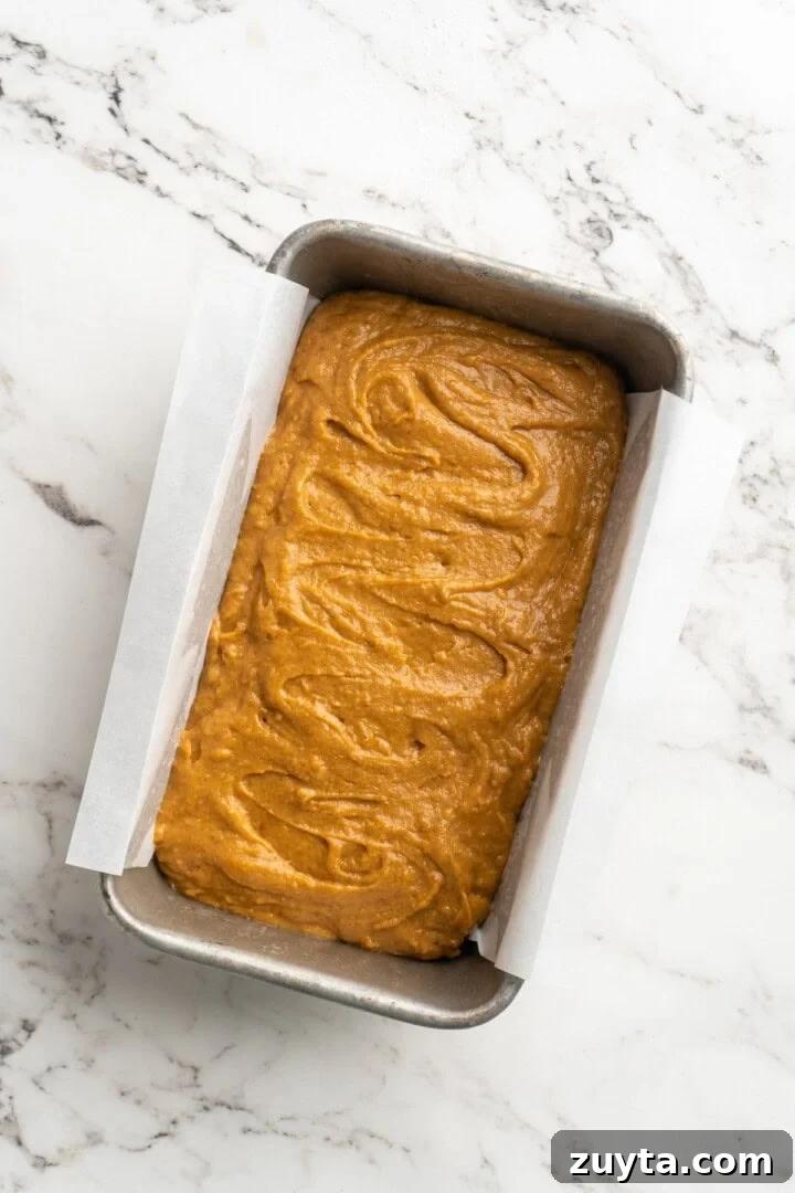 Fill baking pan. Overhead view of pumpkin bread batter in pan