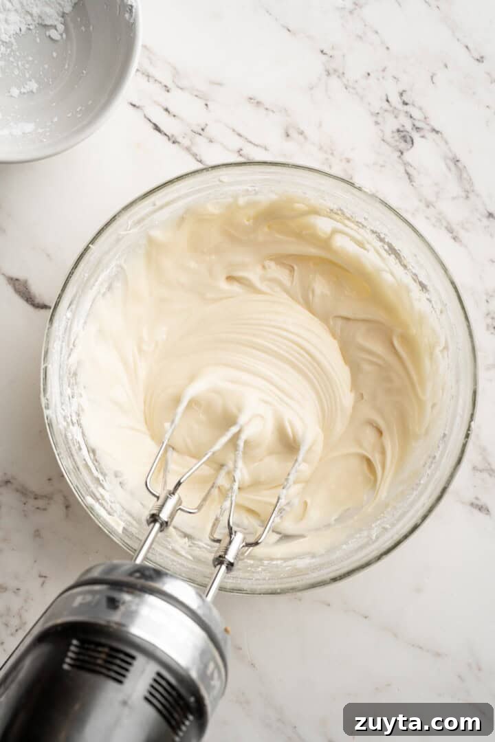 Make frosting. Overhead view of hand mixer beating cream cheese frosting