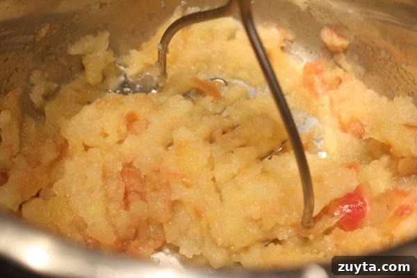 Homemade Instant Pot Applesauce Recipe 5 Potato masher mashing apples.