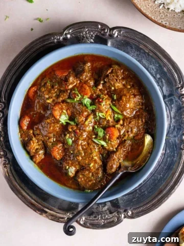 A bowl of beef masala in a tray on a flat surface.