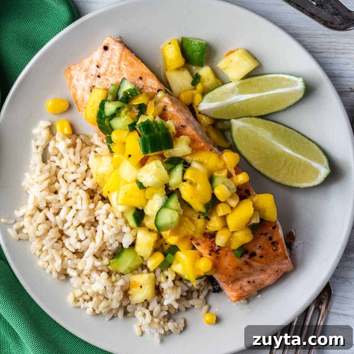 Soy-Ginger Salmon Stir-Fry with Vegetables 13 plate with salmon fillet topped with mango pineapple salsa, brown rice, and lime wedges.