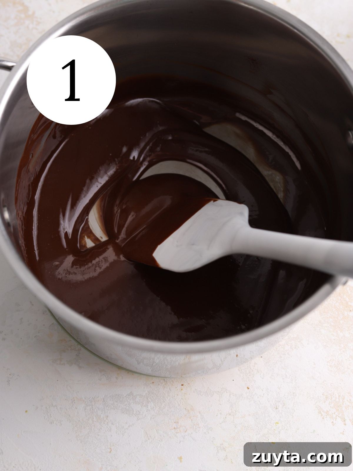 Fudgy Brownie Crinkle Cookies Recipe 3 A saucepan with melted chocolate and a spatula.