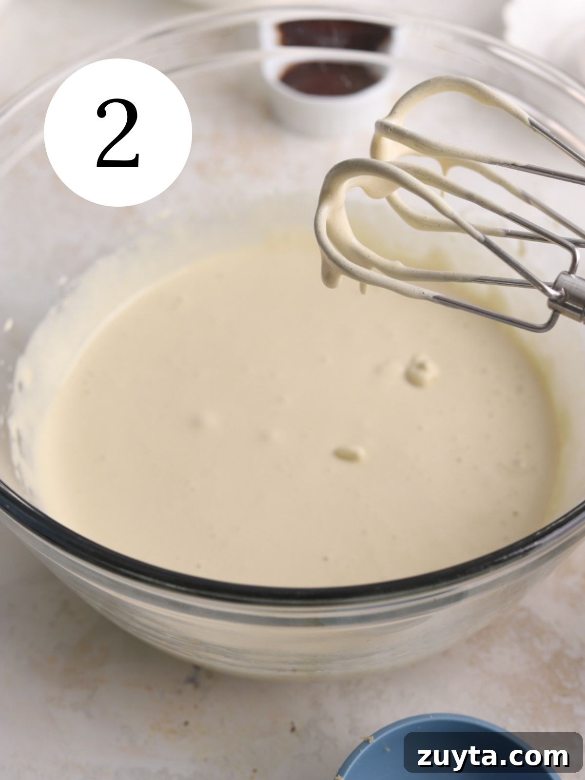 Fudgy Brownie Crinkle Cookies Recipe 4 A large glass bowl with eggs and sugar mixed together with a mixer.