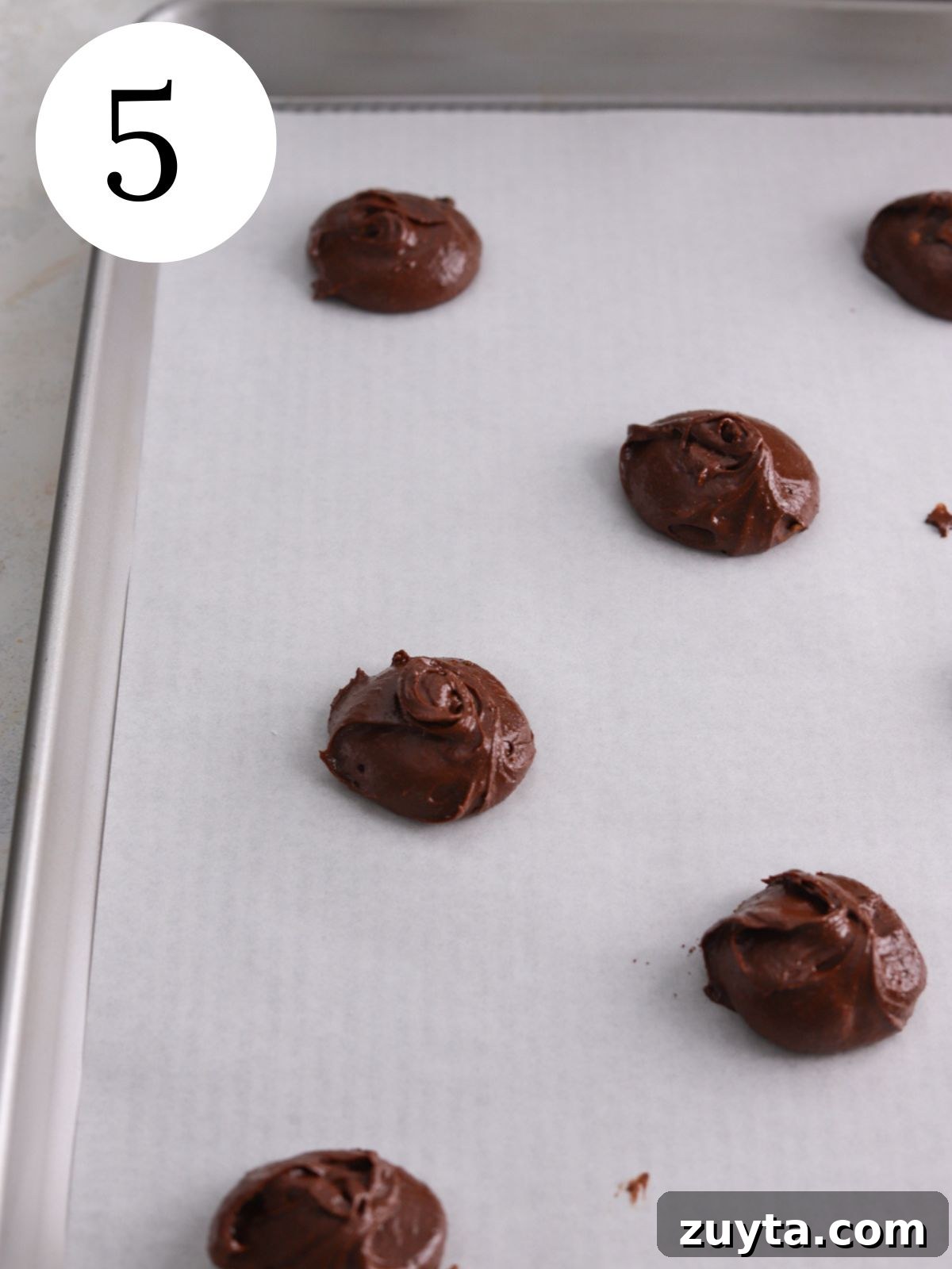 Fudgy Brownie Crinkle Cookies Recipe 5 Chocolate cookie dough balls on a baking sheet.