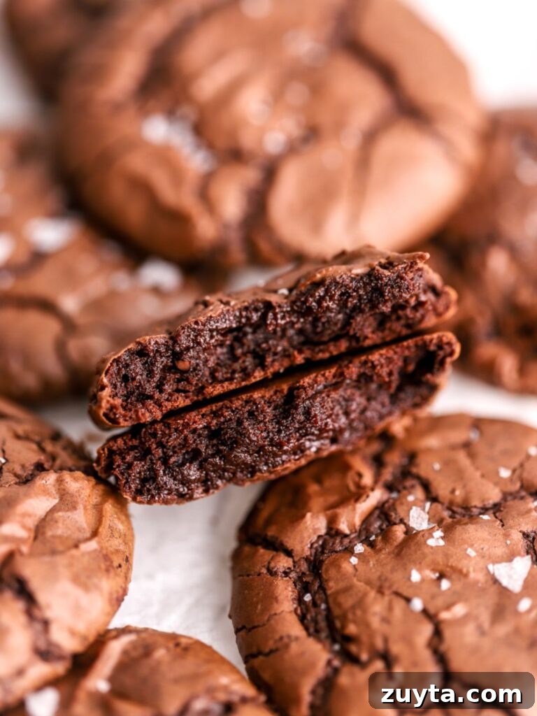 Fudgy Brownie Crinkle Cookies Recipe 7 A chocolate cookie split in half and a batch of chocolate cookies.